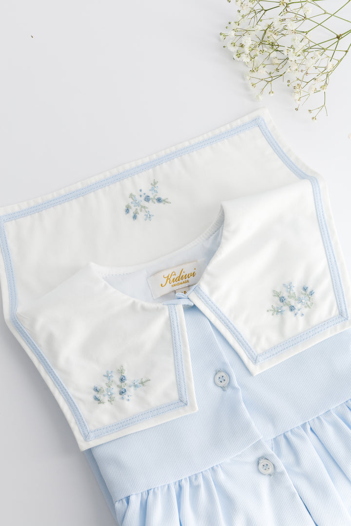 Light blue dress with white collar and floral embroidery on a light gray background