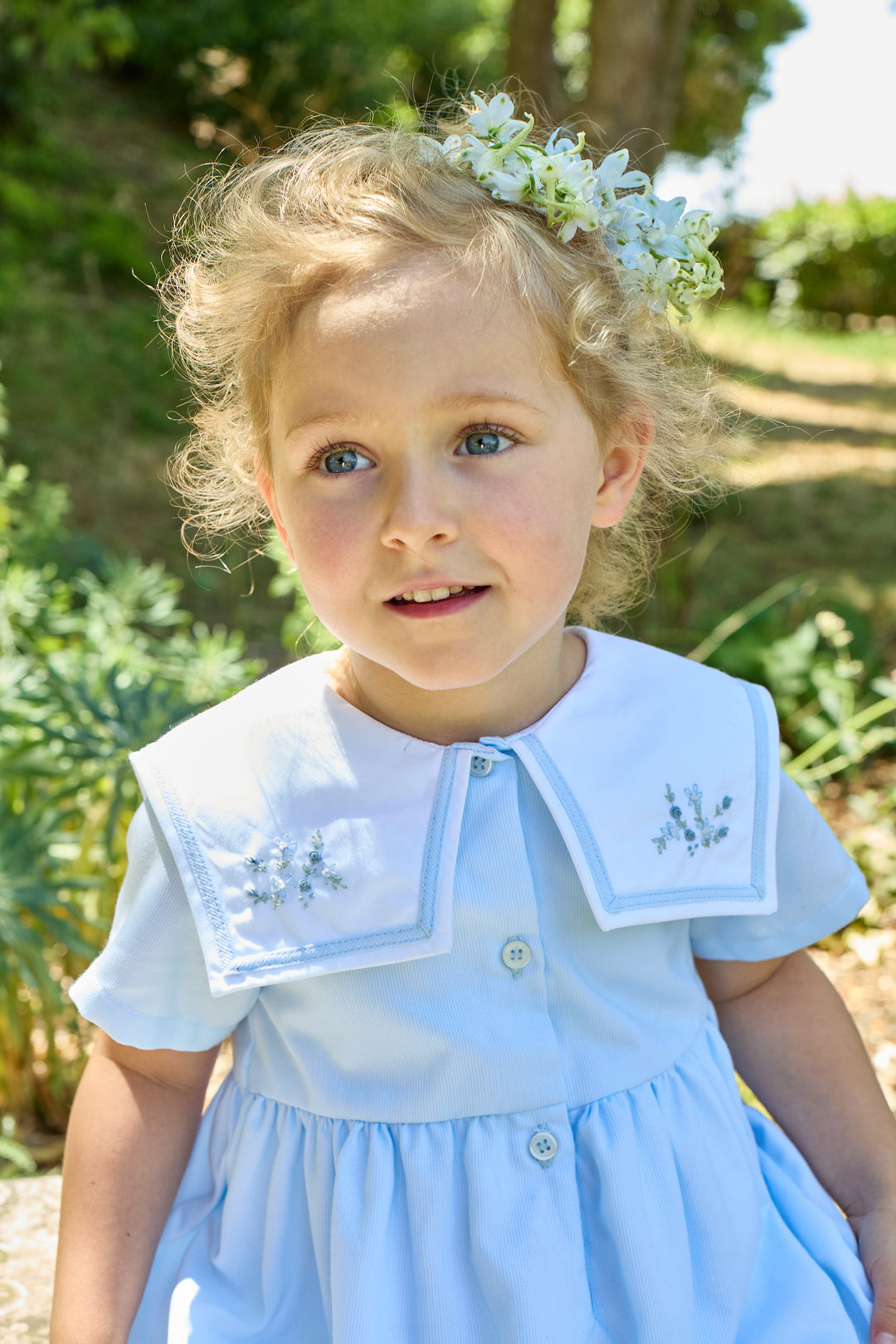 Young girl in a light blue dress with floral accents outdoors