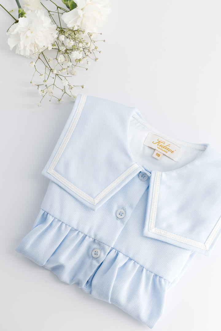 Light blue baby outfit with ruffled details on a white background