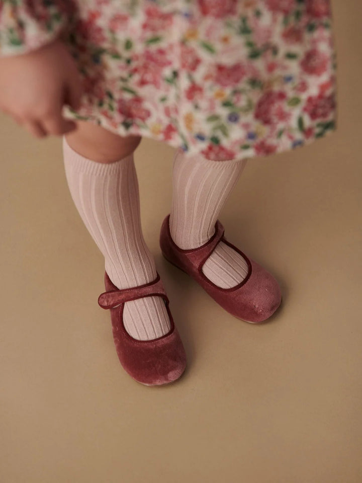 Girl wearing pink floral dress with pale pink knee high socks and pink mary jane shoes