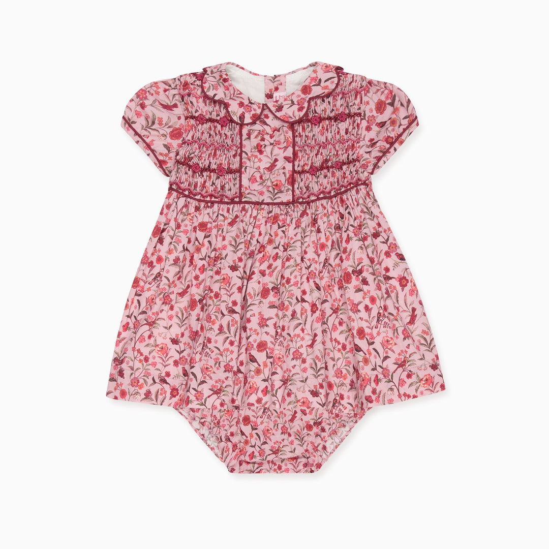 A baby girl's short-sleeve dress in a pink and red floral print with smocked detailing on the chest and collar, shown flat on a white background.