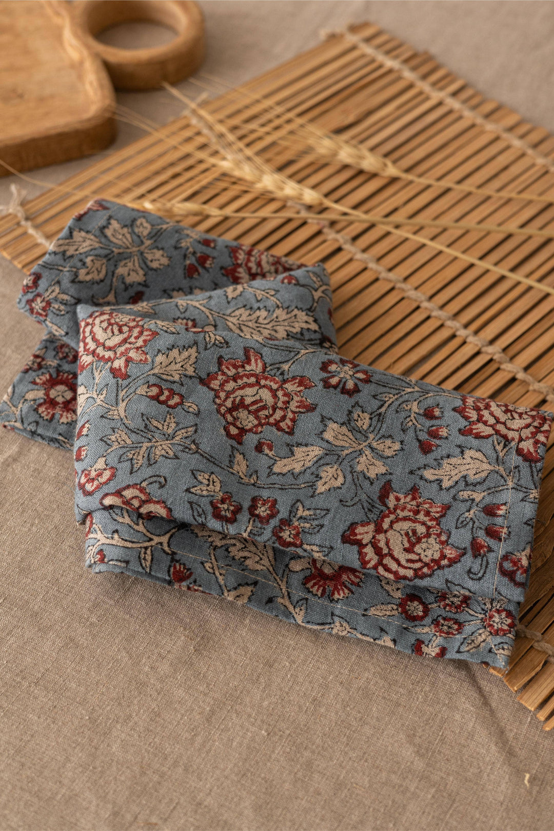 Floral-patterned fabric on a woven mat with a wooden object in the background
