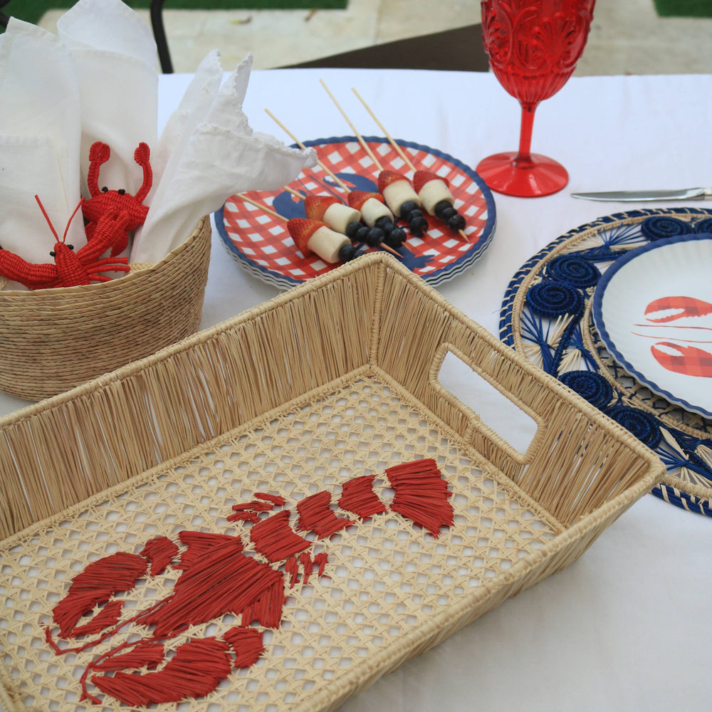 Woven tray with red lobster design on a table with other decorative items.