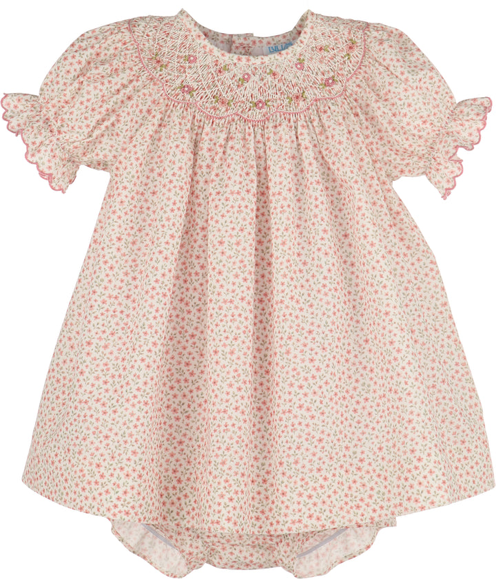 A baby girl's short-sleeve smocked dress in a light pink and green floral print, featuring ruffled sleeves and a smocked yoke with pink embroidery.