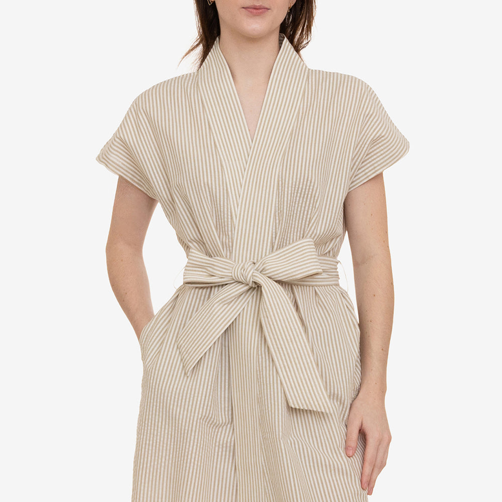 Woman wearing a beige striped dress with a belt on a white background