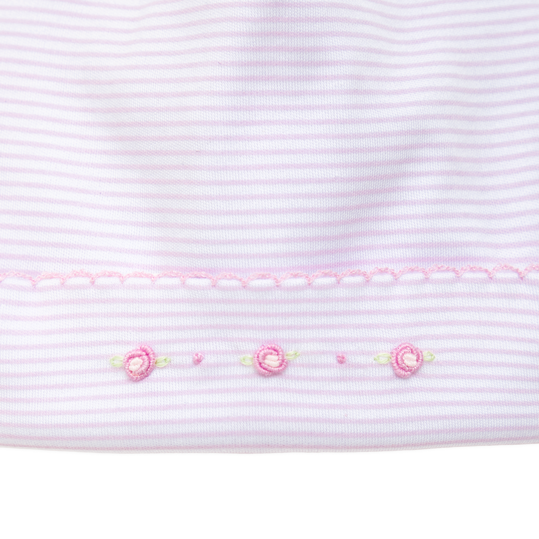 Close-up of pink striped fabric with embroidered flowers on a white background