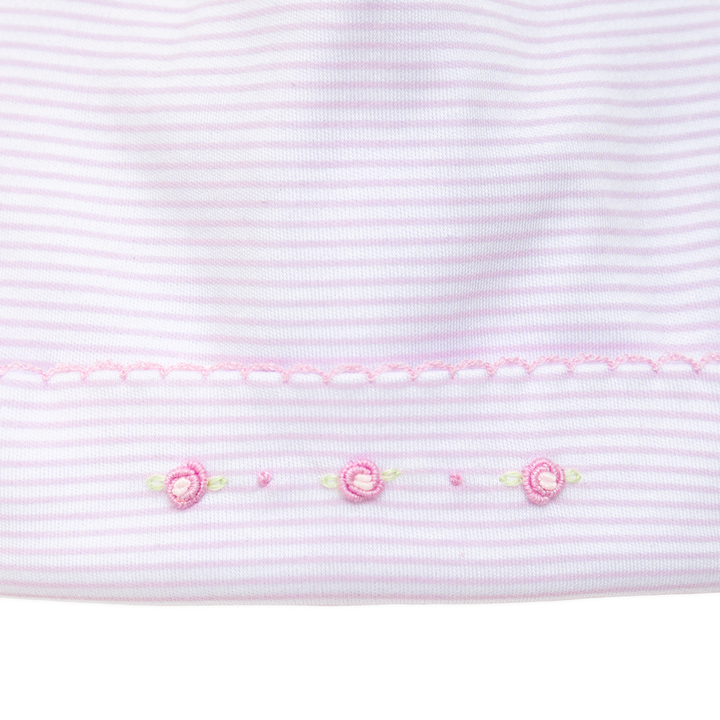 Close-up of pink striped fabric with embroidered flowers on a white background