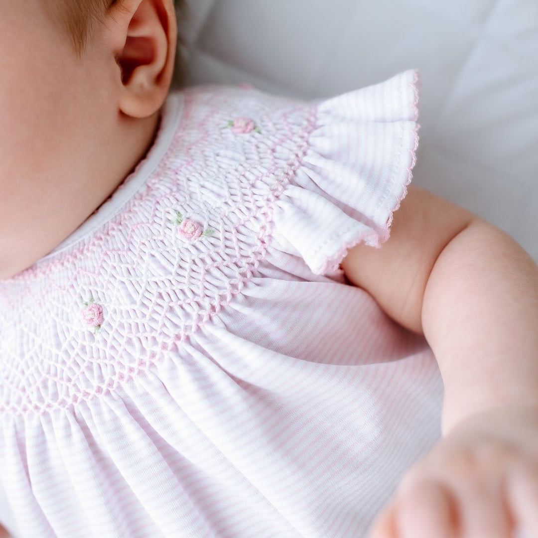 Close-up of a baby wearing a pink embroidered dress with a blurred background