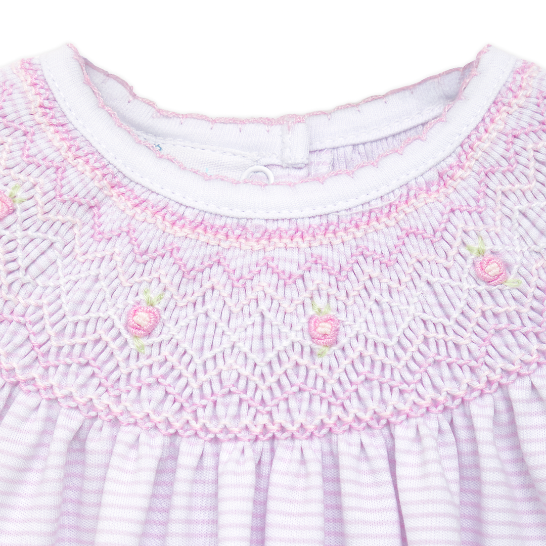 Close-up of a baby dress with pink smocked collar and white background