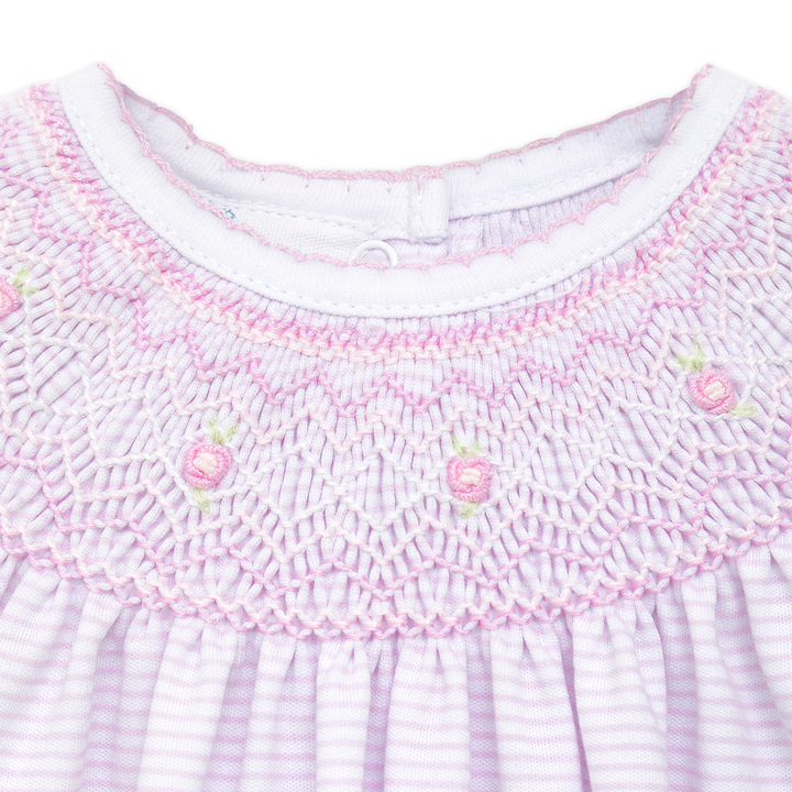 Close-up of a baby dress with pink smocked collar and white background