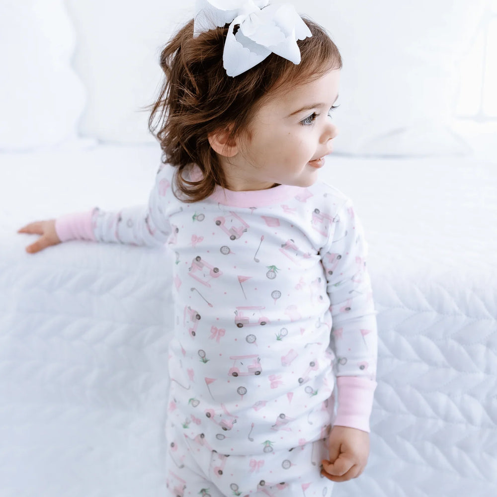 Child wearing a patterned onesie with pink sleeves on a white background