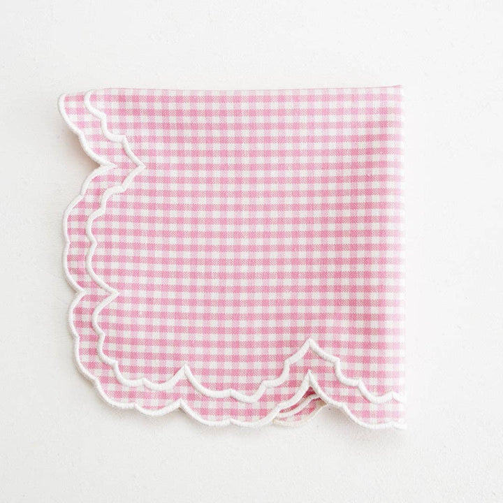 Pink gingham napkin with scalloped edge on a white background