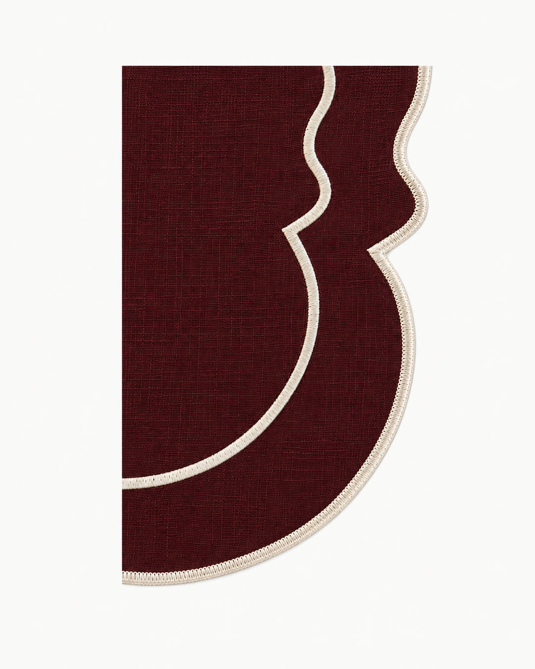 A close-up of a burgundy fabric product with a scalloped edge and cream-colored trim, shown against a plain white background.