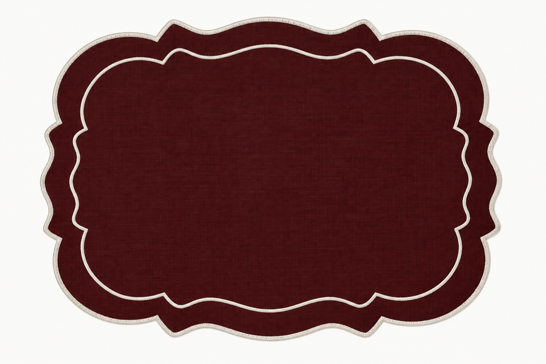 A rectangular placemat with a scalloped border in dark burgundy and cream, shown flat against a white background.