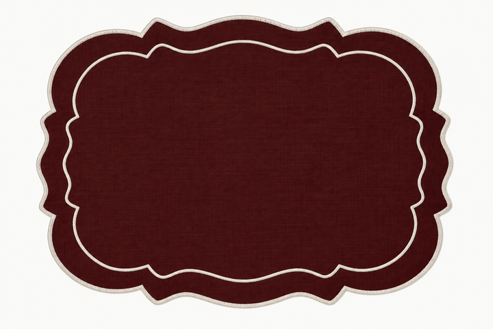 A rectangular placemat with a scalloped border in dark burgundy and cream, shown flat against a white background.