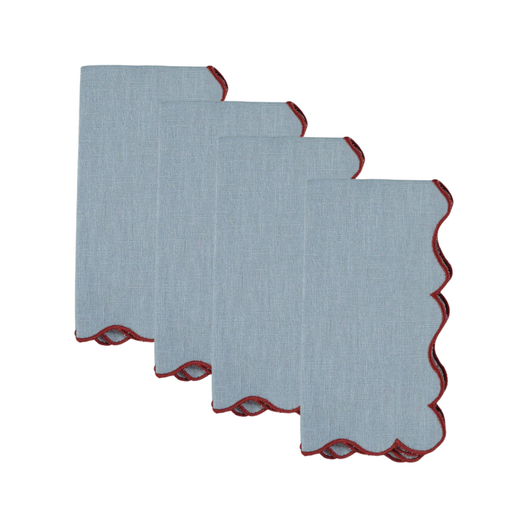 Four light blue linen napkins with scalloped edges and a contrasting red inner lining, arranged in a staggered stack on a white background.