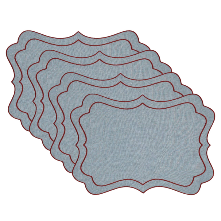 A set of 4 matching rectangular placemats with decorative scalloped edges, fanned out on a plain white background. The placemats have a textured light blue surface with a thin dark red border.