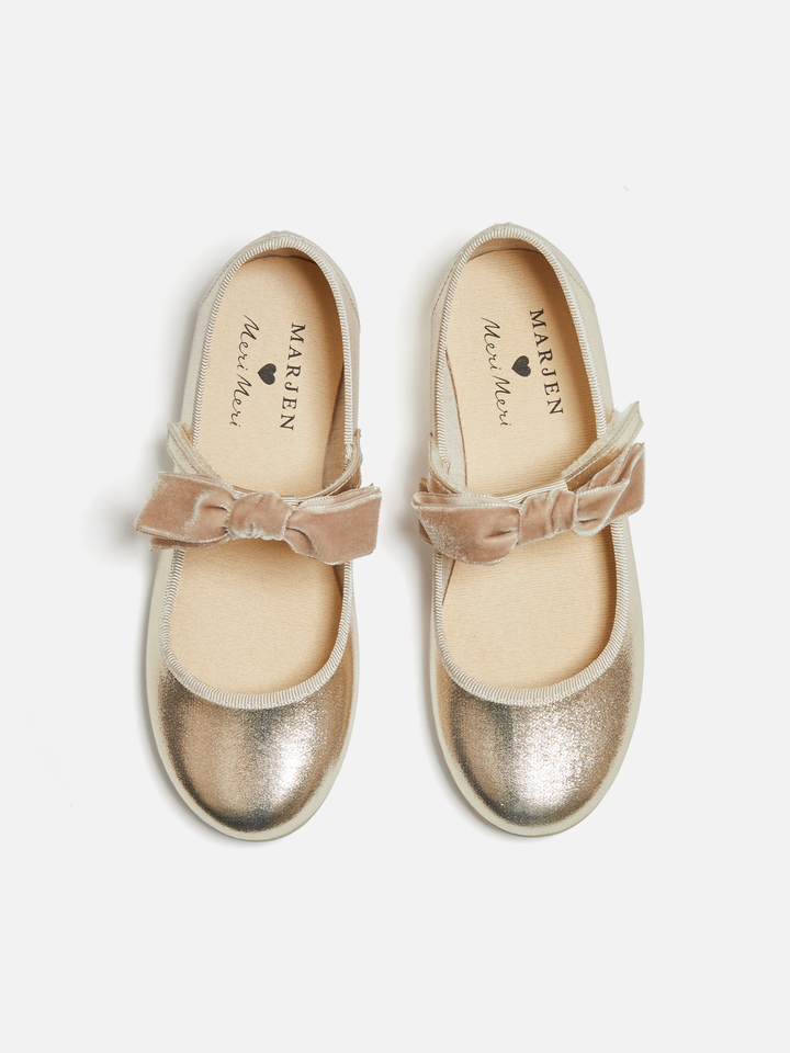 A pair of metallic gold ballet flats with dusty pink velvet bow straps, shown from a top-down view on a light gray background. The brand name 'MARJEN' is visible on the insoles.