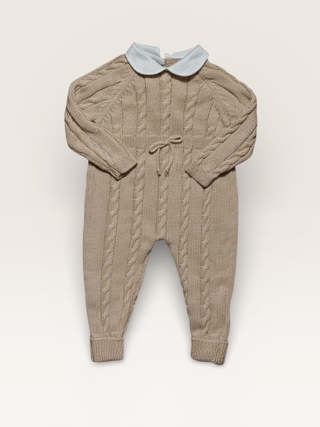 A baby's long-sleeve cable-knit jumpsuit in taupe with a contrasting light blue Peter Pan collar, laid flat against a warm off-white background.