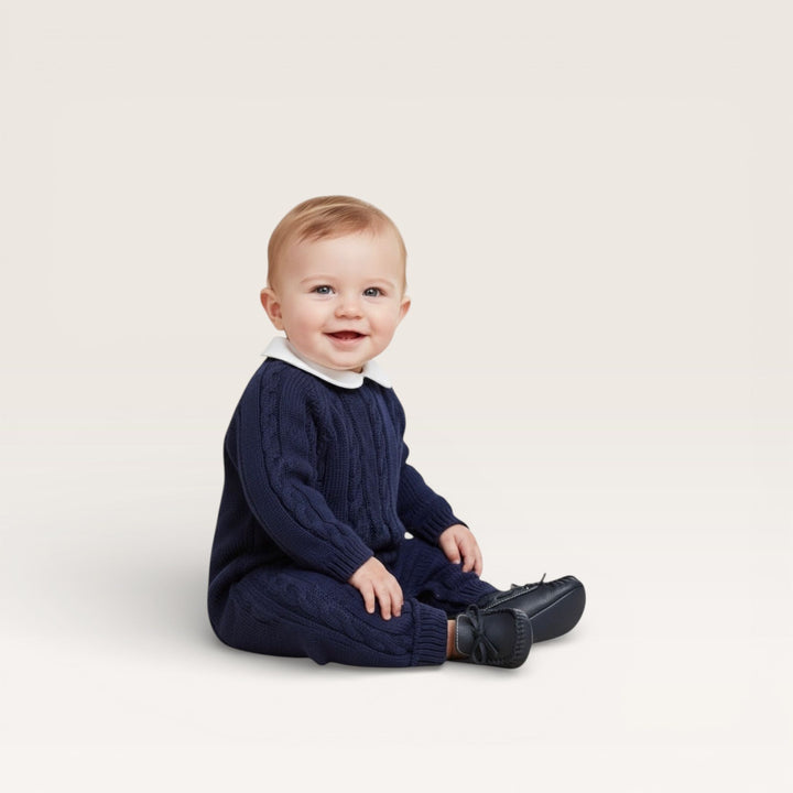 Baby boy sitting with a navy peter pan collar cable knit romper