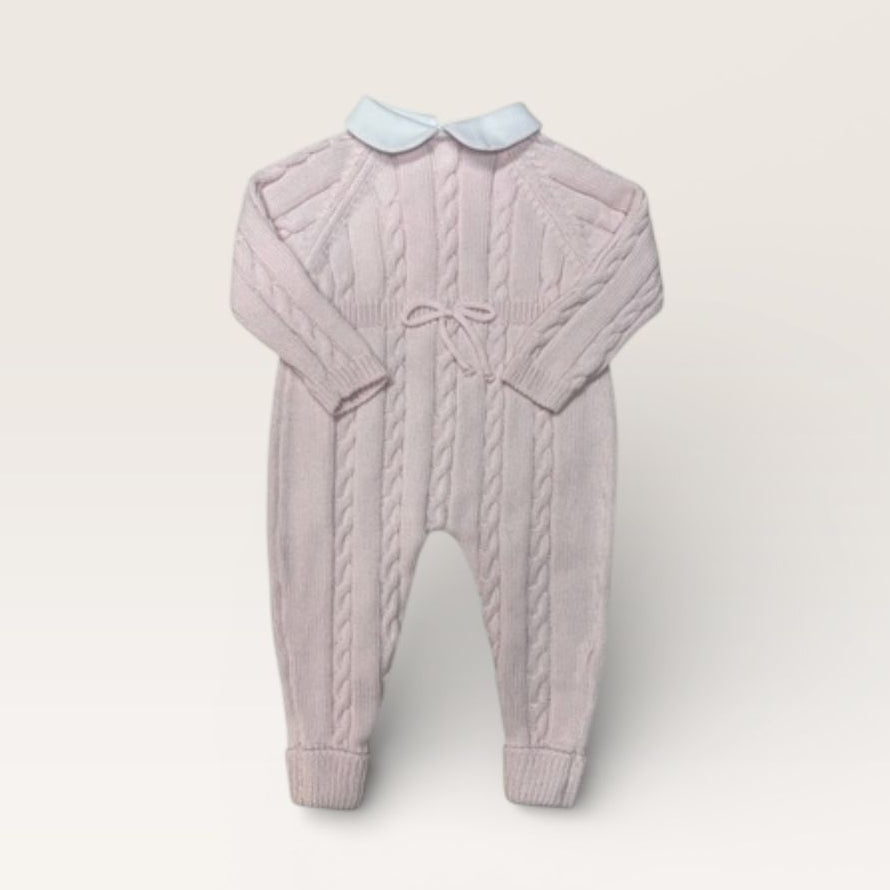A baby cable-knit jumpsuit in a dusty lavender-pink color, featuring a light blue Peter Pan collar and a matching bow at the chest, displayed on a neutral cream background.