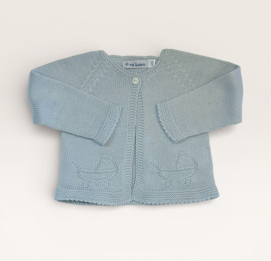 A light blue knit baby cardigan with long sleeves, a single button closure, and knitted basket motifs near the hem, laid flat on a light beige background.
