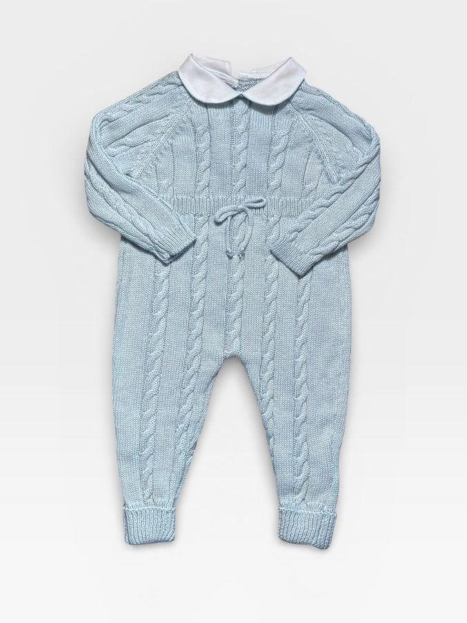 A light blue cable-knit baby jumpsuit with a white Peter Pan collar and a drawstring tie at the chest, laid flat on a light gray background.