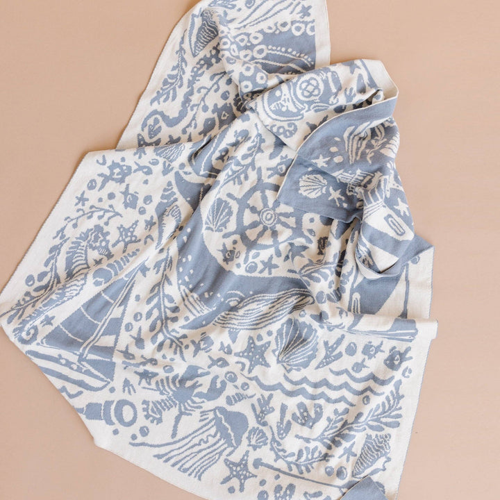 Folded fabric with blue and white nautical pattern on a beige background
