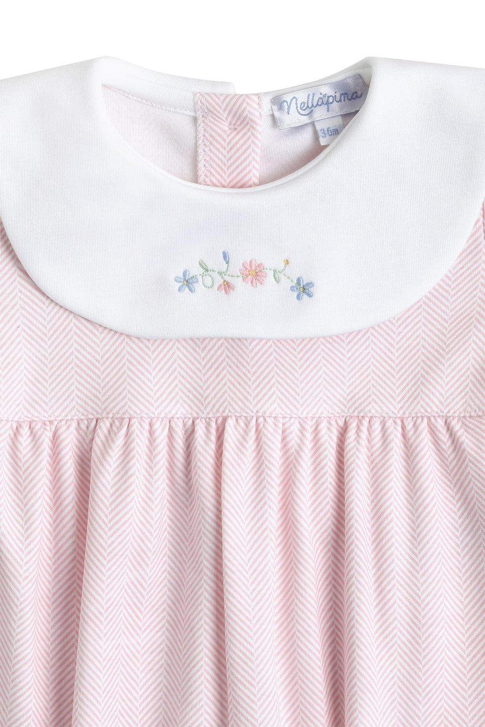 Close-up of a light pink and white herringbone dress with a white Peter Pan collar featuring delicate multicolor floral embroidery.