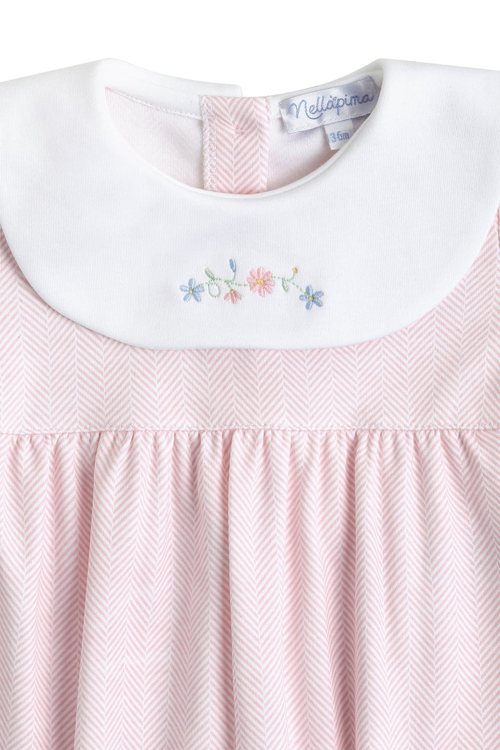 Close-up of a light pink and white herringbone dress with a white Peter Pan collar featuring delicate multicolor floral embroidery.