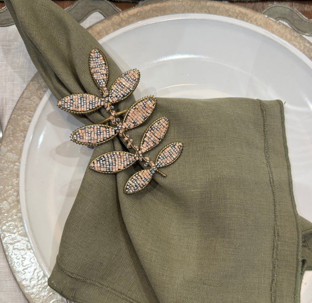 Decorative leaf-shaped napkin ring on a green napkin over a white plate.
