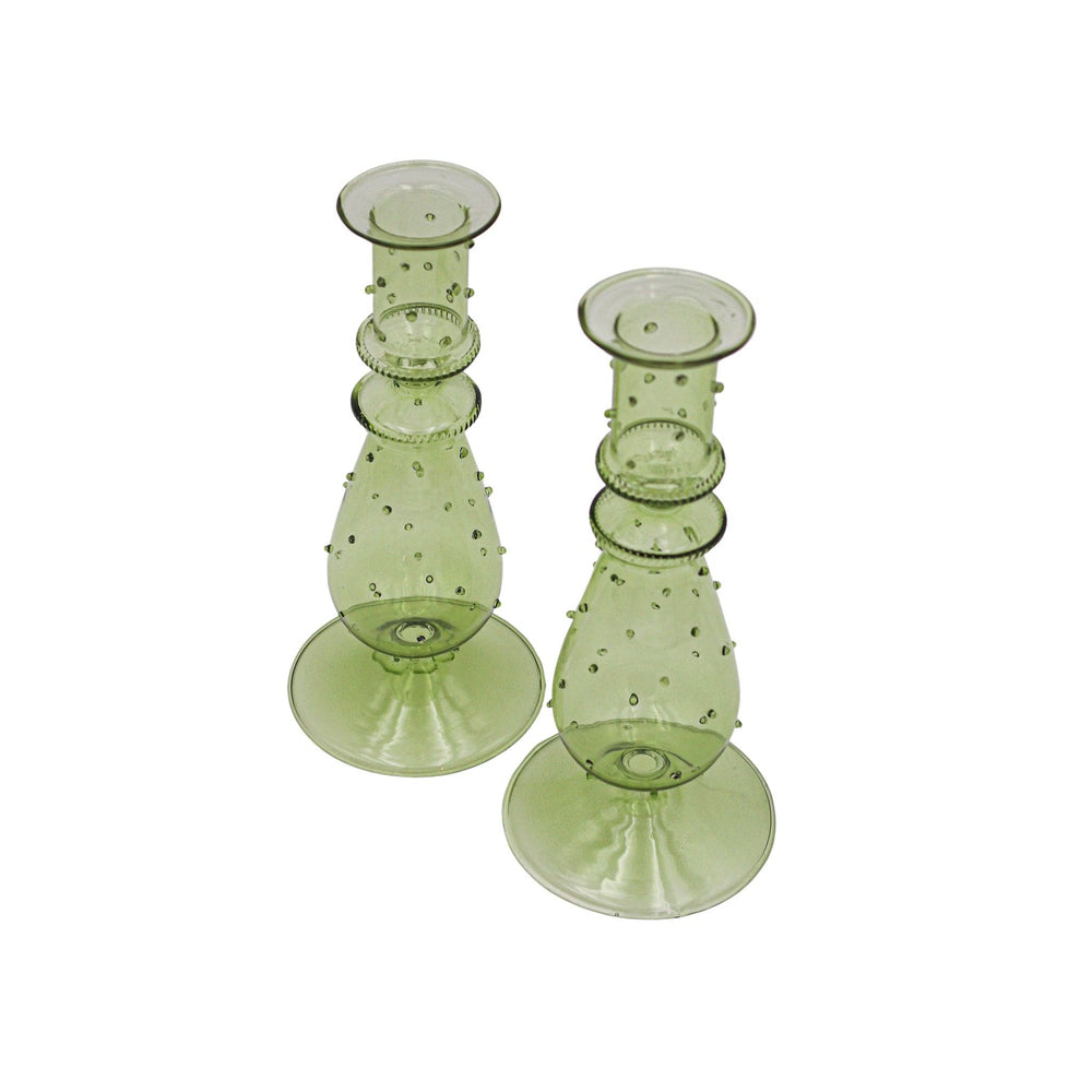 Two green glass candle holders with textured design on a white background
