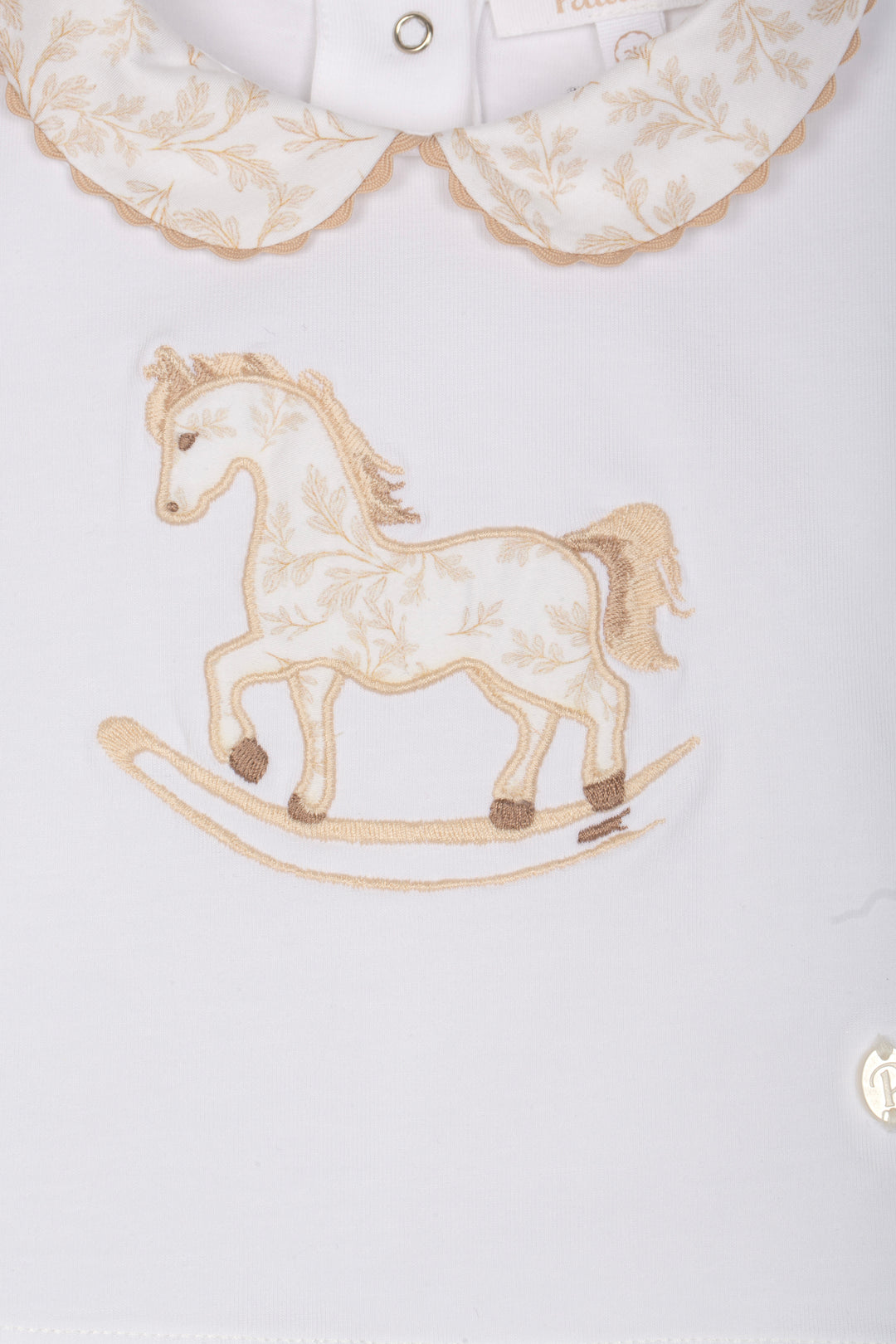 Embroidered rocking horse design on a white shirt with lace collar.