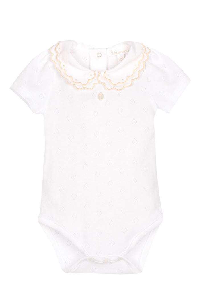 White baby onesie with beige embroidery on a white background