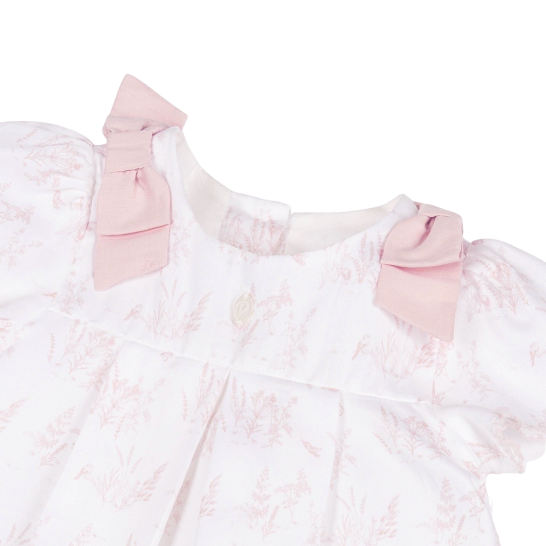 Pink lace dress with bow details on a white background