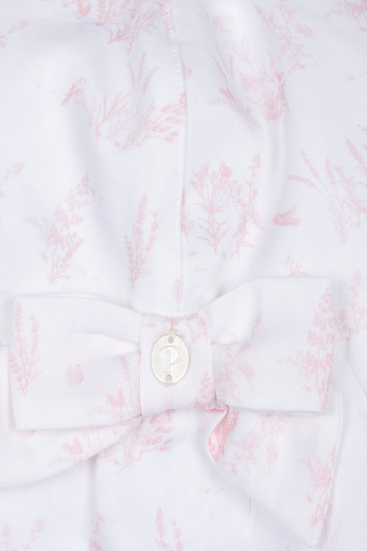 Close-up of a white shirt with pink floral pattern and a button on a white background