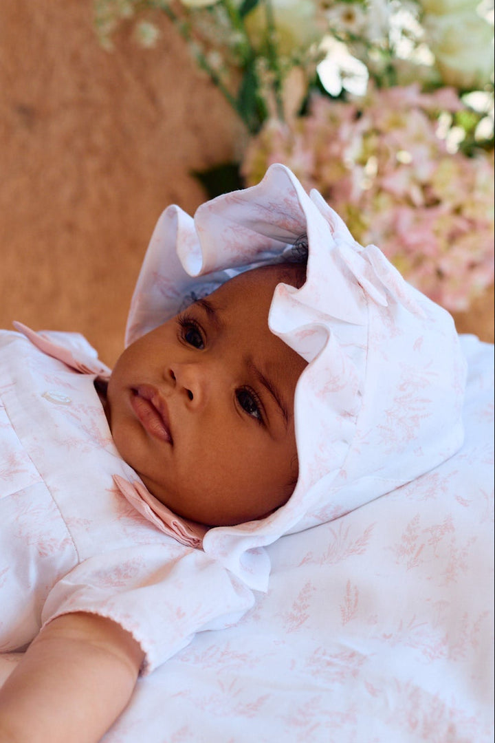 Baby lying on a white blanket with floral decorations in the background
