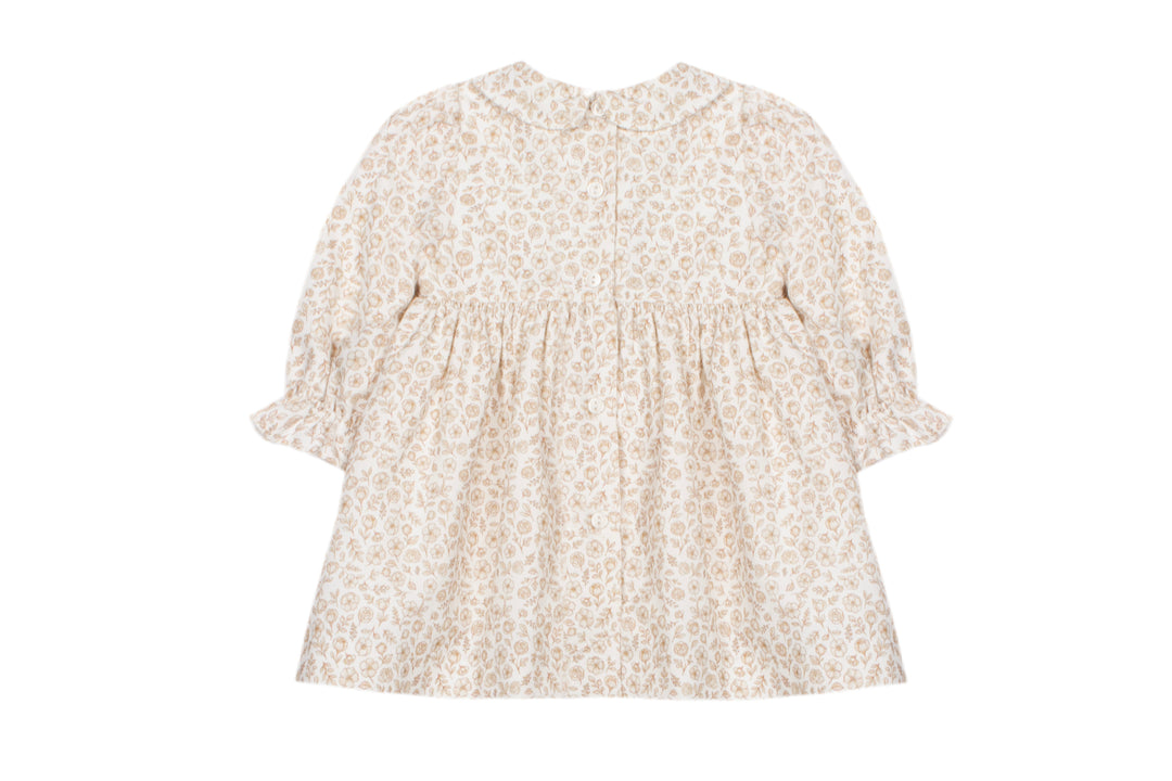 A baby girl's long-sleeve dress with a beige and white floral pattern, featuring a smocked bodice and ruffled sleeves, shown against a plain white background.