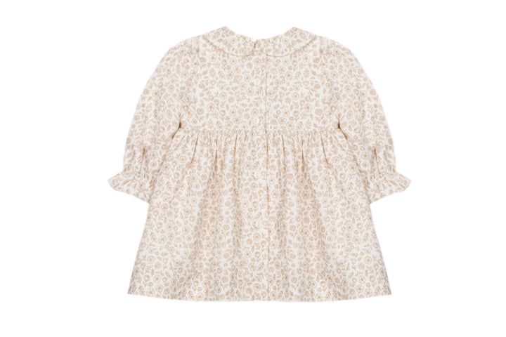 A baby girl's long-sleeve dress with a beige and white floral pattern, featuring a smocked bodice and ruffled sleeves, shown against a plain white background.