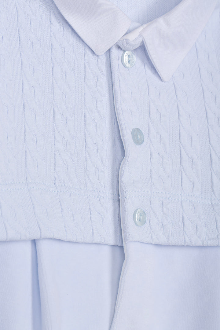 Close-up of a light blue collared shirt with a textured, vertically pleated front panel and smooth button-down lower section.