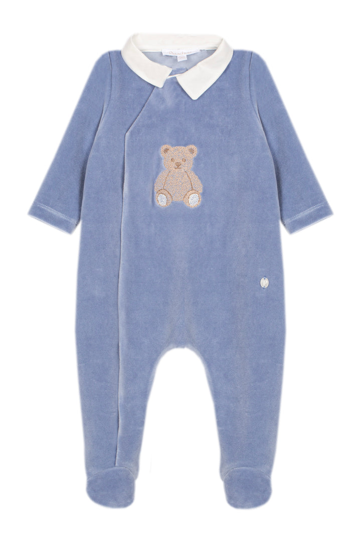 A baby footed sleeper in dusty blue velour with a white collar and an embroidered teddy bear on the chest, shown against a plain white background.