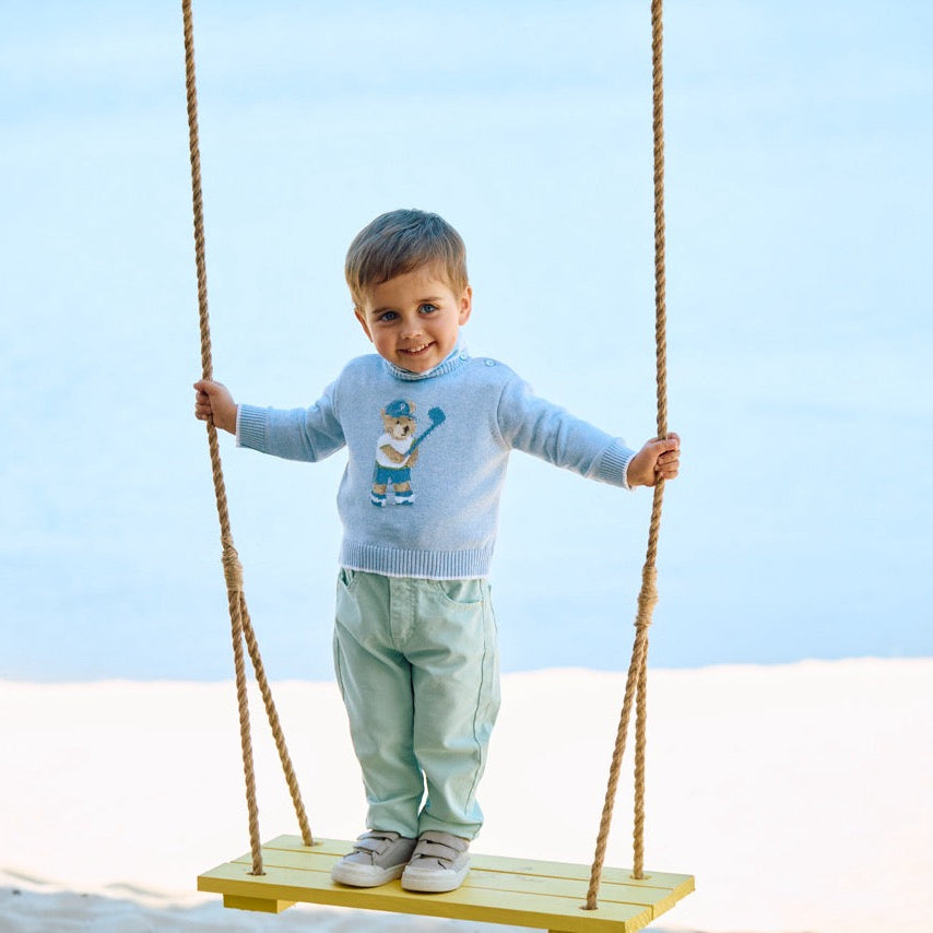 Child on a swing against a clear blue sky