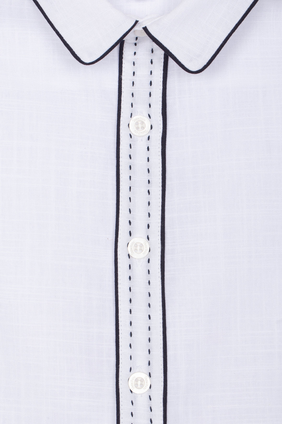 Close-up of a white shirt with black trim and buttons on a light gray background