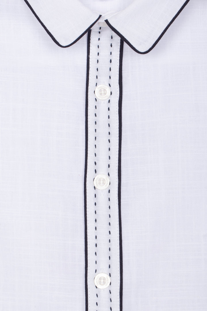 Close-up of a white shirt with black trim and buttons on a light gray background