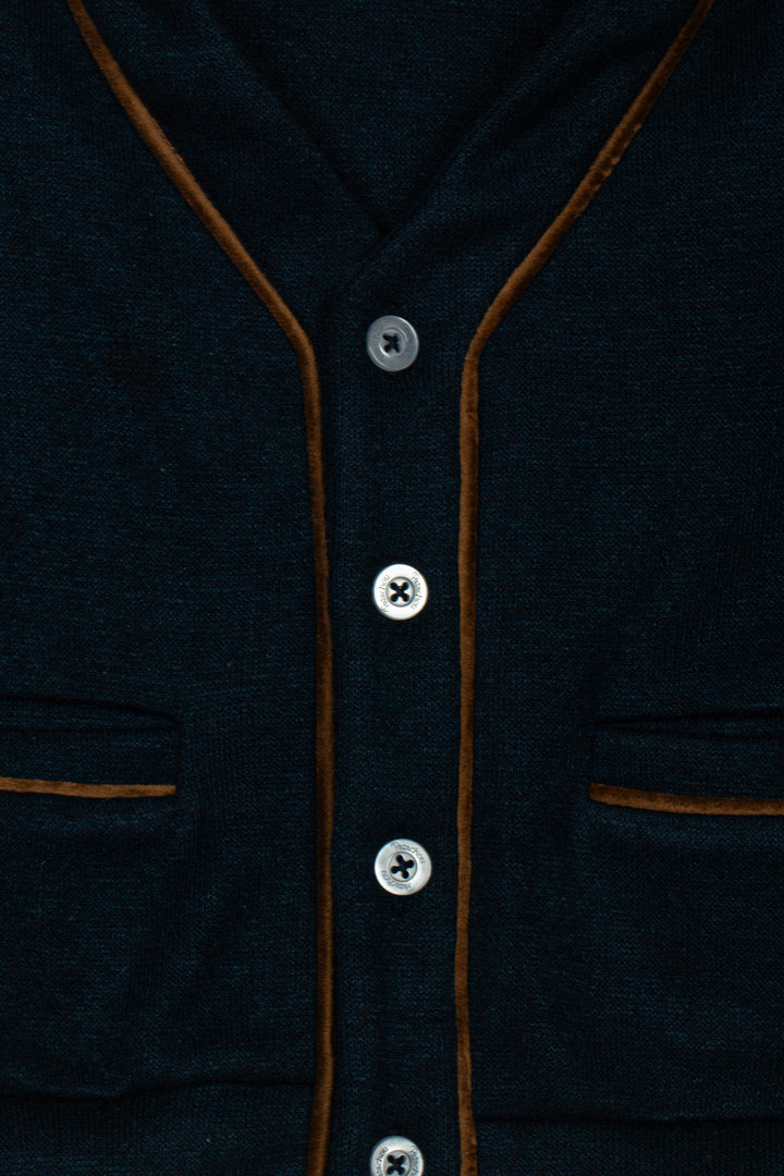 Close-up of a dark navy knit cardigan with brown contrast piping and silver buttons.