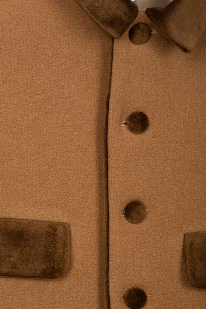 Close-up detail of a brown wool-like jacket or coat showing a button closure, collar, and pocket flaps.