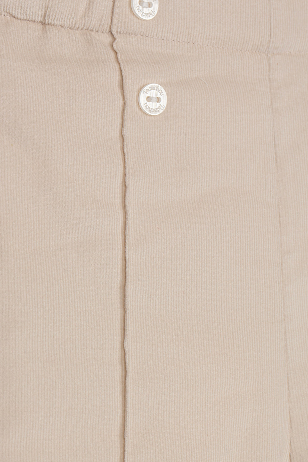 Close-up of a beige ribbed fabric garment with two white buttons on a front placket.