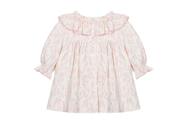 A baby girl's long-sleeve dress with a ruffled collar, featuring a delicate pink damask pattern on a warm cream background.