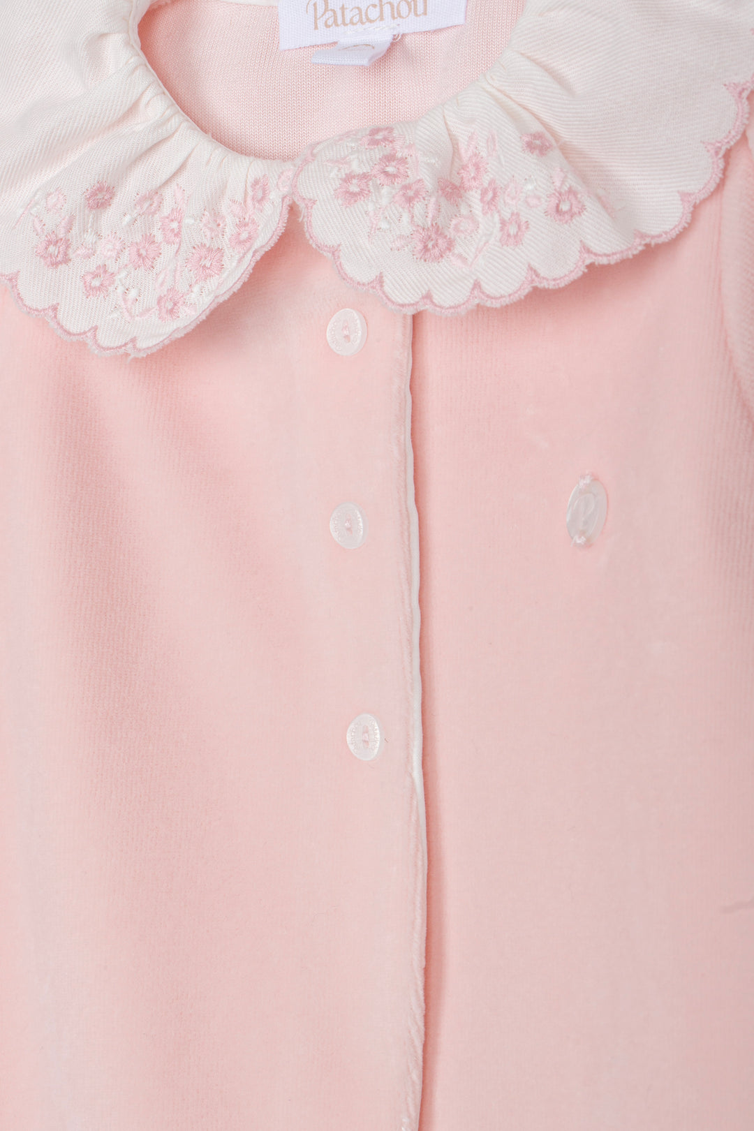 Close-up of a pale pink baby top with a white embroidered Peter Pan collar and white buttons, showing the Patatchou brand label.