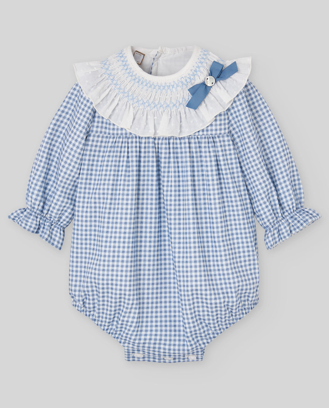 A baby long-sleeve romper in a light blue and white gingham pattern, featuring a white smocked ruffled collar with a blue bow accent.